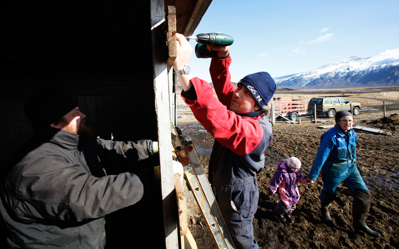 Thorgerthur Thorkellsdottir walks with her mother Anna Runoltsdottir (R), as Thorkell Eiriksson (L) and his brother-in-law Petur Runottsson work to seal a sheep barn, in case winds shift and volcanic ash from a volcano erupting across the valley lands on their farm, in Eyjafjallajokull on April 17. The current season is when the spring lambs are born and such young animals are especially susceptible to volcanic ash in their lungs so they must be stored inside. (Reuters)