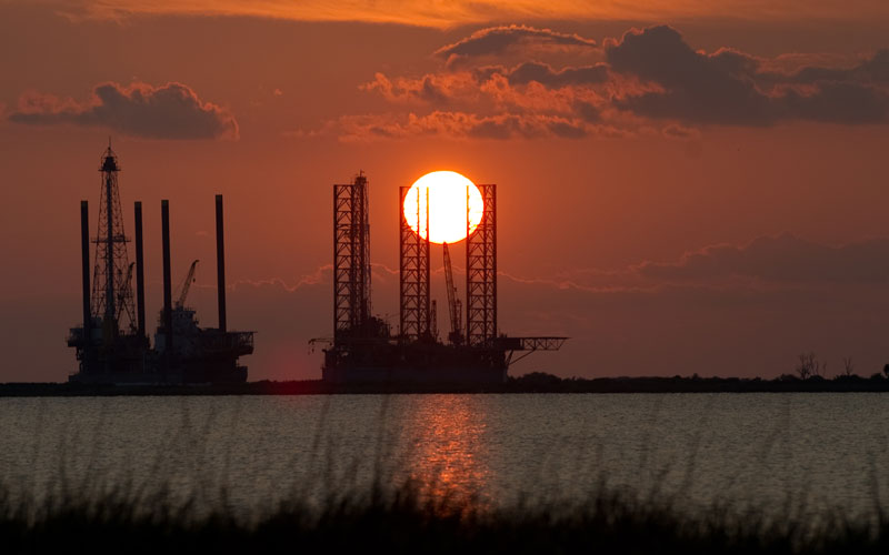 The sun sets behind two under construction offshore oil platform rigs in Port Fourchon, Louisiana, June 14, 2010, as cleanup continues on the BP Deepwater Horizon oil spill. (AFP)