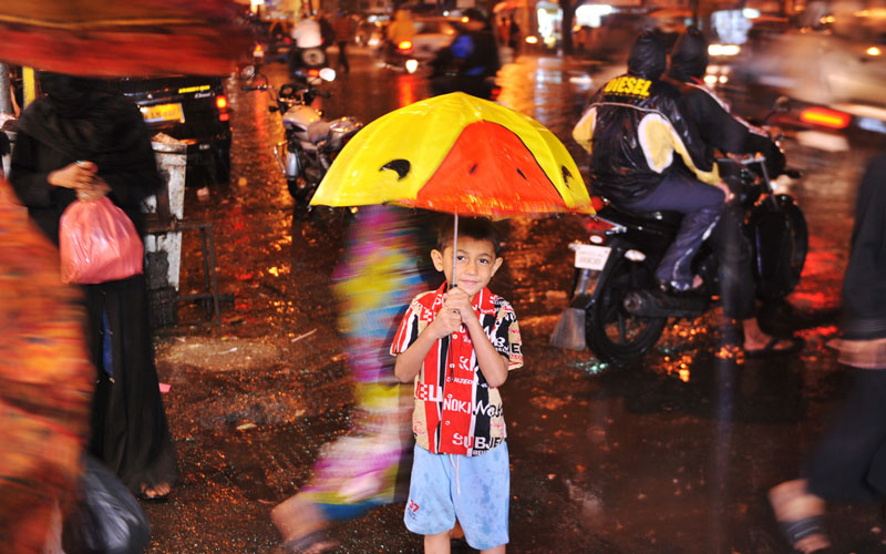 A young Indian boy shelters under an umbrella as pedestrians face a downpour in Mumbai. The monsoon season, which runs from June to September, accounts for about 80 per cent of India's annual rainfall. (AFP)