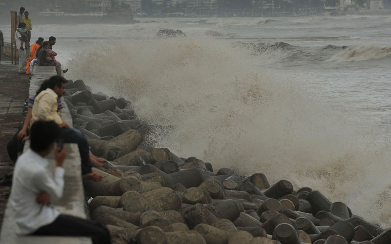 People sit by the seafront watching the waves roll in to Mumbai. The monsoon season, which runs from June to September, accounts for about 80 percent of India's annual rainfall.  (AFP)