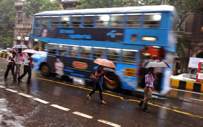 A doubledecker bus passes pedestrians sheltering under umbrellas during a downpour in Mumbai.  The monsoon season, which runs from June to September, accounts for about 80 per cent of India's annual rainfall. (AFP)