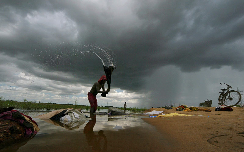 A washer man beats clothes on a rock in the Daya River as monsoon clouds hover over Bhubaneswar, India. The monsoon season in India begins in June. Last year India's summer monsoon, vital for agriculture because of the rainfall it brings, was the weakest since 1972. (AP)