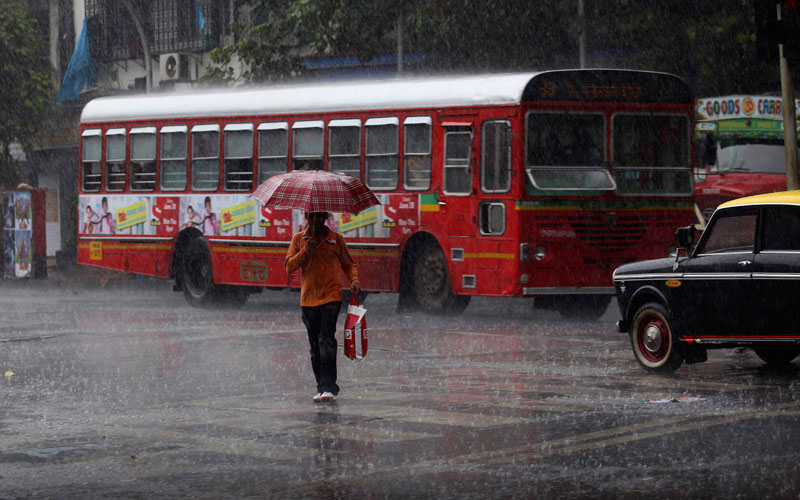 A man crosses a busy street in the rain in Mumbai, India. Monsoon rains, crucial for India's agriculture, have revived after being stalled by cyclone Phet, weather officials said. (AP)