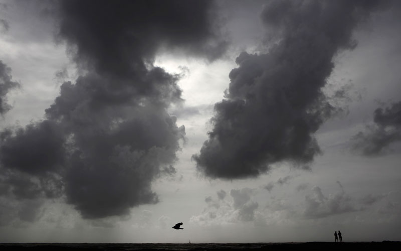 Boys walk on the shores of the Arabian Sea as monsoon clouds are seen on the horizon in Mumbai, India. (AP)