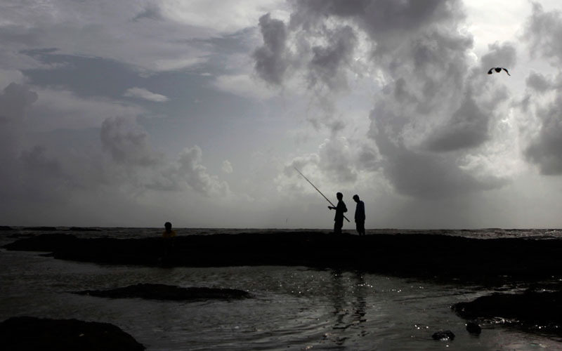 Boys try to catch fish along the shores of the Arabian Sea with monsoon clouds in background in Mumbai, India, Monday, June 7, 2010. (AP)