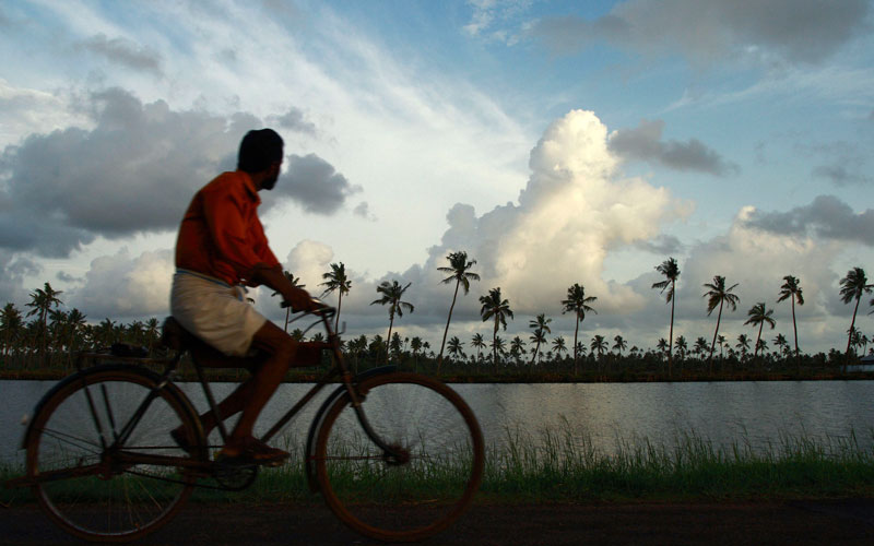 A man rides a bicycle against the backdrop of monsoon clouds on the outskirts of the southern Indian city of Kochi in kerala, India. (REUTERS)