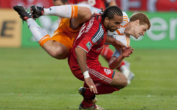 Houston Dynamo's Andrew Hainault, top, lands on Toronto FC's Dwayne DeRosario after his header during second-half MLS soccer game action in Toronto. (AP)