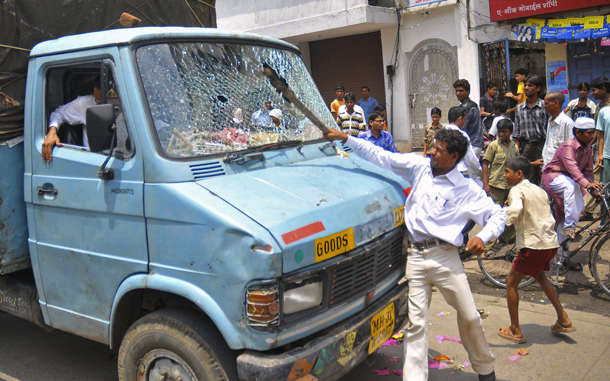 A goods truck driver (L) reacts as a rioter smashes the windshield of his vehicle during a nationwide strike in Ahmedabad. An opposition-led strike over fuel price rises disrupted life across India, triggering transport mayhem and sporadic violence in major cities where schools and businesses closed down. (AFP)