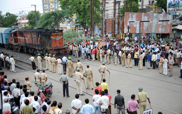 Onlookers watch as Railway Protection Force officials (in khaki uniform) guard a passing goods train at the Maninagar railway crossing during a nationwide strike in Ahmedabad. An opposition-led strike over fuel price rises disrupted life across India, triggering transport mayhem and sporadic violence in major cities where schools and businesses closed down. (AFP)