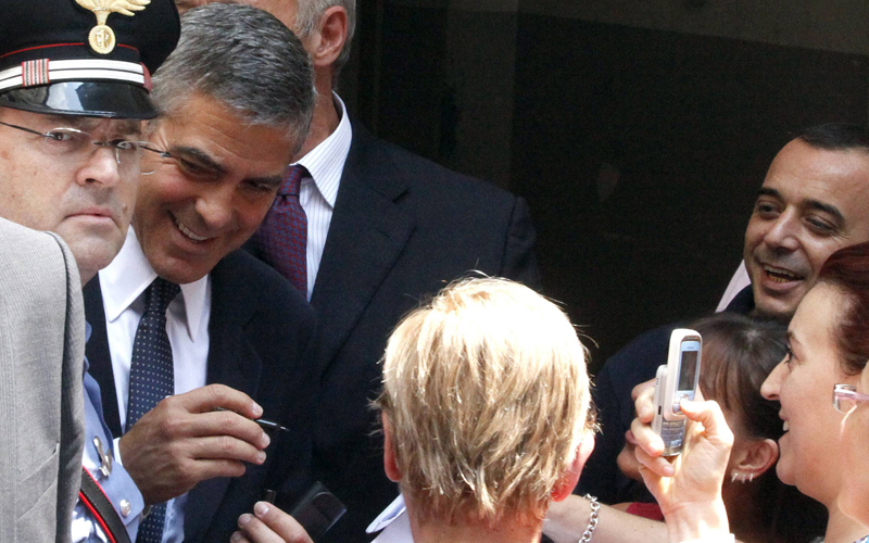 George Clooney signs autographs as he leaves the court in Milan on Friday. ""Don't crush my lawyers," he quipped. (REUTERS)