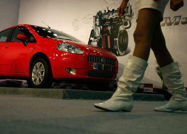 A model walks in front of a Fiat Grande Punto 90HP car displayed at the Hyderabad International Auto Show in Hyderabad, India. (AP)