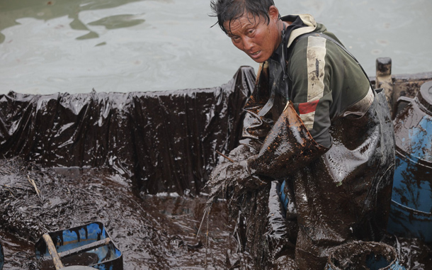 Fisherman clearing oil in the Chinese port of Dalian. Chinese authorities have closed several beaches and an island resort near the major port of Dalian as they try to clean up an oil spill that has affected crude shipments, state media said. (AFP)