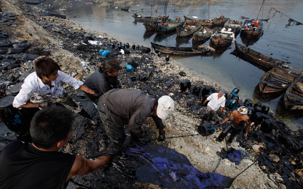 Local fishermen work to clean up the oil, which has spread far from the original explosion site in Xingang port, Dalian, northeastern China. The first details emerged Friday on the cause of China's largest reported oil spill, while environmentalists urged the government to do more to warn local residents of potential danger, saying children are playing still off nearby beaches. (AP)