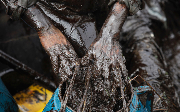 A fisherman cleans up oil near an oil spill site in Dalian, Liaoning province. A chemical agent used to strip sulphur from oil contributed to the pipeline blast at China's Dalian port last weekend, causing the huge oil slick in the sea and forcing the port's temporary closure, the country's work safety watchdog said in a preliminary report. (REUTERS)