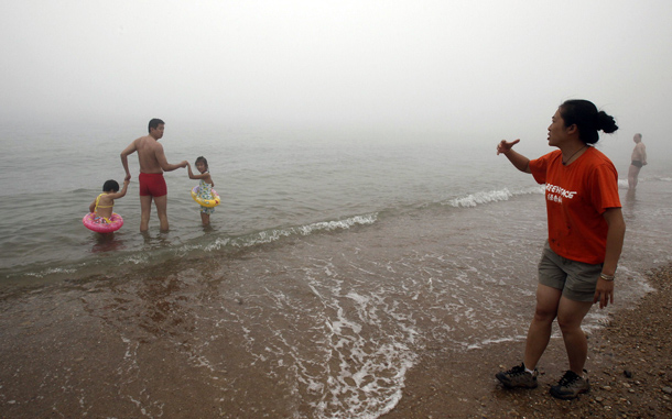 Greenpeace activist warning visitors not to swim in the oil-contaminated water in Dalian. Chinese authorities have closed several beaches and an island resort near the major port of Dalian as they try to clean up an oil spill that has affected crude shipments, state media said. (AFP)