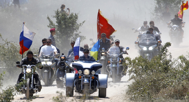 Russia's Prime Minister Vladimir Putin (C) rides a Harley Davidson Lehman Trike decorated with the Russian and Ukrainian national flags as he arrives for the meeting with motorbikers at their camp near Sevastopol in Ukraine's Crimea. (AFP)