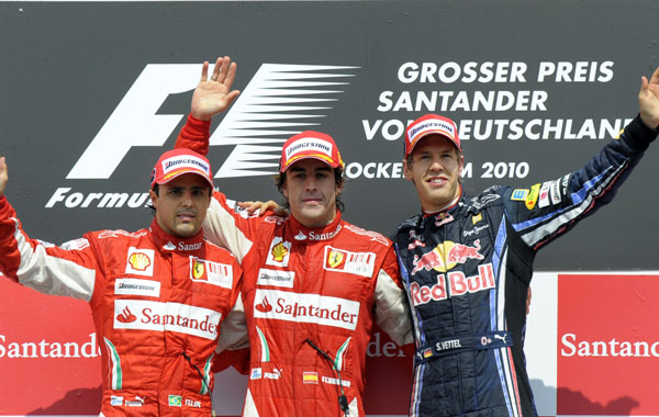 Ferrari's Spanish driver Fernando Alonso (C), Ferrari's Brazilian driver Felipe Massa (L) and Red Bull's German driver Sebastian Vettel pose on the podium of the Hockenheimring circuit in Hockenheim, after the Formula One German Grand Prix. (AFP)