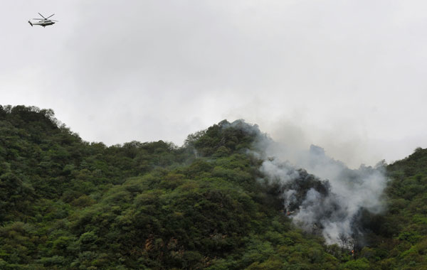 A Pakistani rescue helicopter flies over smoke and wreckage of a crashed passenger plane in The Margalla Hills on the outskirts of Islamabad. A Pakistani passenger plane with 150 people on board crashed in a ball of flames in densely wooded hills while trying to land in Islamabad during bad weather, aviation officials said. (AFP)