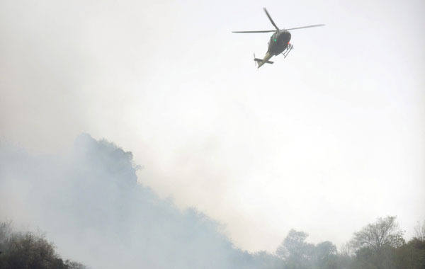 A Pakistani rescue helicopter flies over smoke and wreckage of a crashed passenger plane in The Margalla Hills on the outskirts of Islamabad. A Pakistani passenger plane with 150 people on board crashed in a ball of flames in densely wooded hills while trying to land in Islamabad during bad weather, aviation officials said. (AFP)