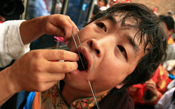 A Tibetan man has his mouth pierced with steel needles during the Lurol festival in Rebkong, known in Chinese as Tongren, in Qinghai province. The annual religious festival is held during the sixth month of the Tibetan lunar calendar with sacrificial performances for the Gods, who visit villagers through human mediums. (REUTERS)