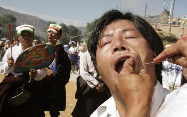 A Tibetan man has his mouth pierced with steel needles by 47-year-old Tibetan, Nambengya, who is possessed by the warrior mountain god Amyesyullha during the Lurol festival in Rebkong. (REUTERS)