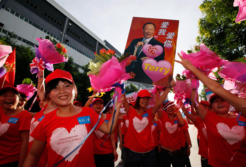 Foxconn workers hold a picture of Terry Gou, chairman of Foxconn Group, with Chinese characters reading, "Love You, Love You," on during a rally to raise morale at the heavily regimented factories inside the Foxconn plant in Shenzhen, south China, Guangdong province. (AP)