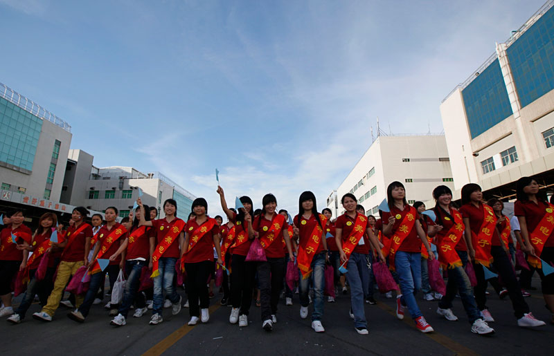 Foxconn workers hold small flags during a rally to raise morale at the heavily regimented factories inside the Foxconn plant in Shenzhen, south China, Guangdong province. (AP)