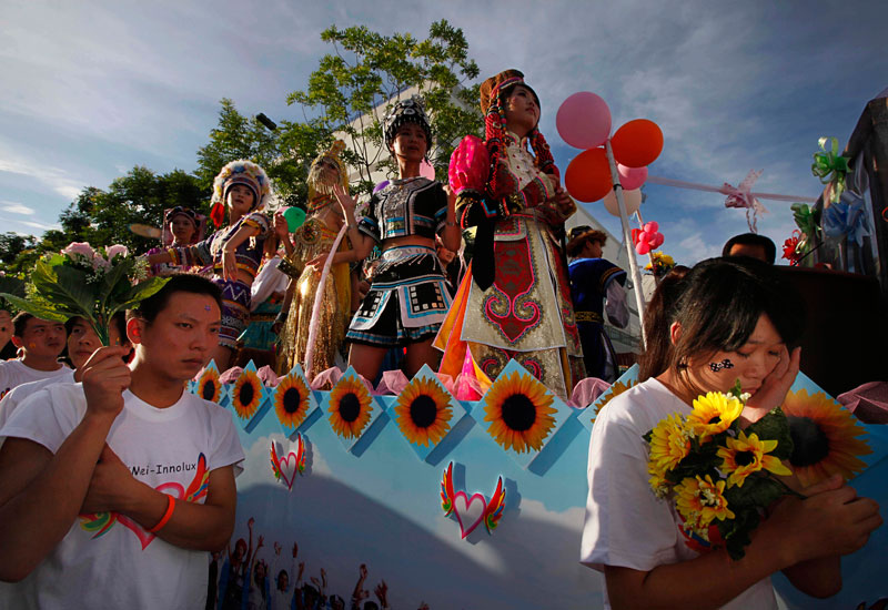 Foxconn workers hold flowers and dress for dancing during a rally as to raise morale at the heavily regimented factories inside the Foxconn plant in Shenzhen, south China. (AP)