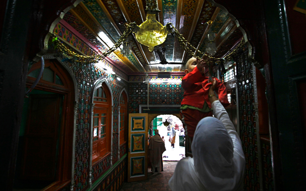 A Kashmiri Muslim woman helps her child to reach the iron chains hanging at the entrance of the shrine of Syed Abdul Qadir Jilani, a scholar who traveled from Iran to Kashmir to spread Islam, in Srinagar, India. Muslims throughout the world are celebrating the holy fasting month of Ramadan, when devout fast from dawn till dusk. (AP)