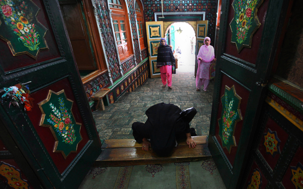 A Kashmiri Muslim woman prays at the entrance of the shrine of Syed Abdul Qadir Jilani, a scholar who traveled from Iran to Kashmir to spread Islam, in Srinagar, India. Muslims throughout the world are celebrating the holy fasting month of Ramadan, when devout fast from dawn till dusk. (AP)