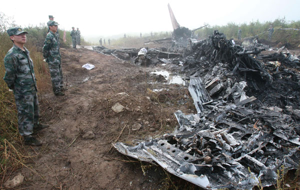Chinese military guard the wreckage of the Henan Airlines ERJ-190 jet made by Brazilian company Embraer which was carrying 96 people after it slammed into the ground on landing in the northeast city of Yichun in remote Heilongjiang province. (AFP)
