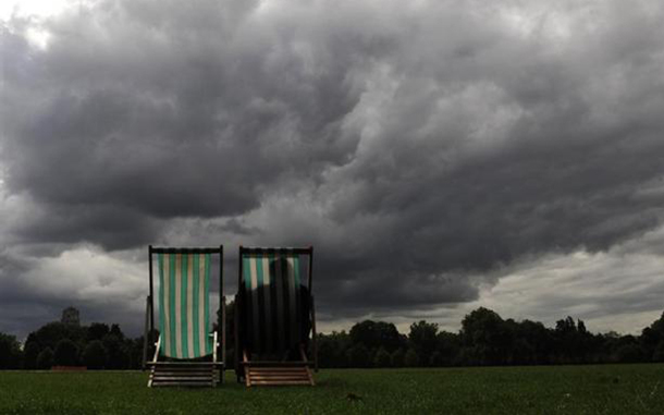 People relax in deckchairs in Hyde Park ahead of the holiday weekend, in London. (REUTERS)