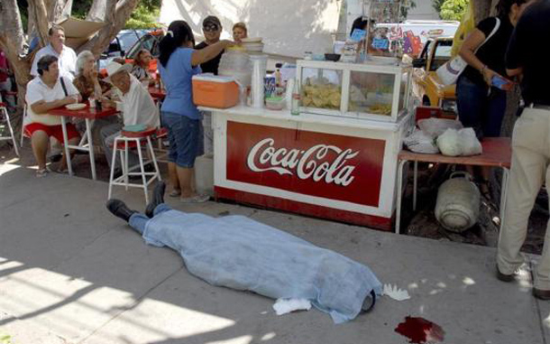 Patrons eat at a taco stand, as the body of a man lies on the pavement, in Ciudad Obregon, Mexico. According to local media, the man died after suffering a fatal heart attack. (REUTERS)