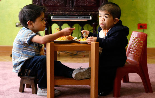 Edward Nino Hernandez (R) eats lunch with his eleven-year-old brother in their home in Bogota. (REUTERS)