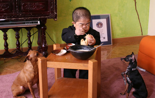 Edward Nino Hernandez, 24, eats breakfast as his dogs look on in his home in Bogota, Colombia. (REUTERS)