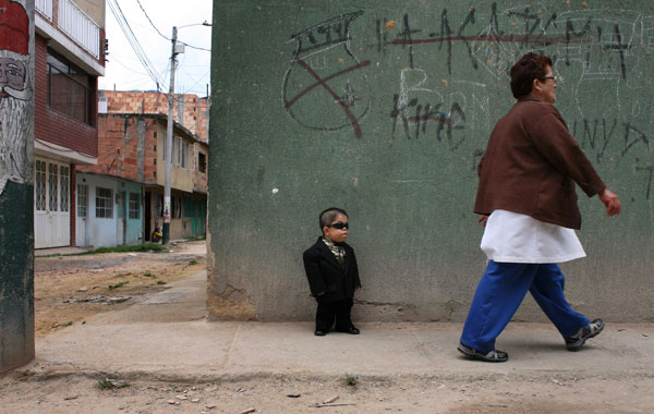 Edward Nino Hernandez, 24, waits outside his home for a ride that will take him to a store where he works as a performer in Bogota, Colombia. (AP)