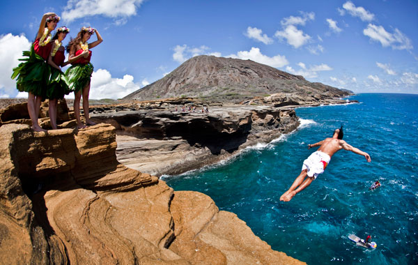 Orlando Duque of Colombia (R) diving from a 16-metre rock at Lana'i Lookout as some local "hula girls" watch in the lead up to the final round of the 2010 Red Bull Cliff Diving World Series in Oahu, Hawaii. (AFP)