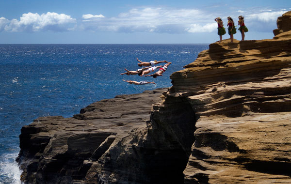 Orlando Duque and Eber Pava of Colombia, Gary Hunt of England, Hassan Mouti of France and Kent De Mond of the US diving from a 16-metre rock at Lana'i Lookout as some local "hula girls" (R) watch in the lead up to the final round of the 2010 Red Bull Cliff Diving World Series in Oahu, Hawaii. (AFP)