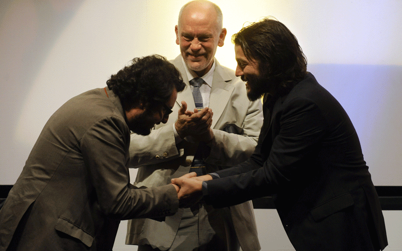 Mexican producer Pablo Cruz (L) shakes hands with Mexican director Diego Luna (R) next to US actor John Malkovich (C) during the presentation of Luna's film "Abel", also produced by Malkovich, during the 58th San Sebastian International Film Festival. (AFP)