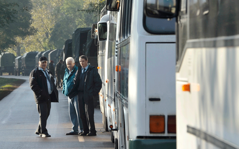 Bus drivers wait beside their buses on a highway to pick up evacuees outside Kolontar, Hungary. (AP)