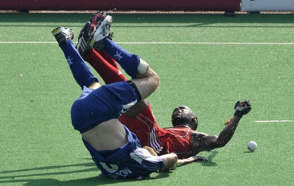 Trinidad and Tobago's Solomon Eccles falls with Graham Moodie (front) of Scotland  during their field hockey match at the Major Dhyan Chand National Stadium during the XIX Commonwealth Games in New Delhi. (AFP)