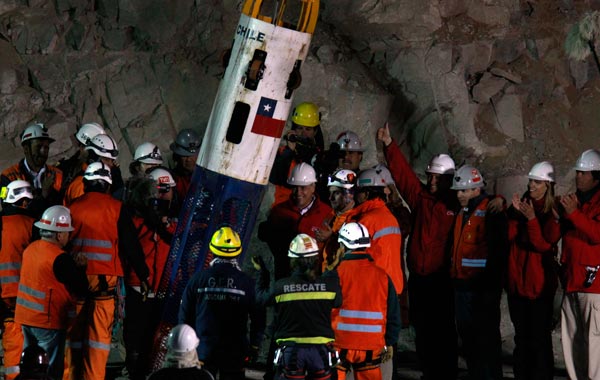 Chilean President Sebastian Pinera, in red jacket next to the capsule,  and other officials and rescue workers greet as rescue worker Manuel Gonzalez Paves is lowered in the capsule into the mine where miners are trapped to begin the rescue  at the San Jose Mine near Copiapo, Chile. (AP)