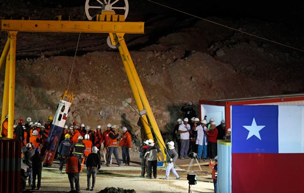 Mining MInister Laurence Golborne and rescue chief Andre Sougarrete, right,  hold hands as rescue worker Manuel Gonzalez Paves is lowered in the capsule into the mine where miners are trapped to begin the rescue  at the San Jose Mine near Copiapo, Chile. (AP)