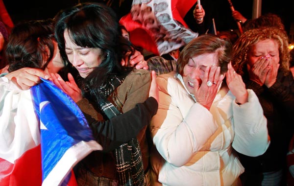 Residents cheer when the first rescuer reached the underground refuge of the miners trapped in the San Jose mine, while watching on a large screen in a public square in Copiapo. (REUTERS)