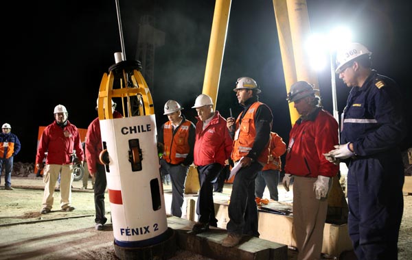 Chilean President Sebastian Pinera (C) watches the first dry run of the descent of the unmanned Fenix 2 rescue capsule, before starting the rescue operation of the 33 trapped miners, at the San Jose mine, near the city of Copiapo, 800 km north of Santiago. (AFP)