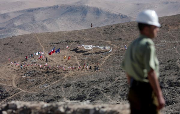 In this photo released by the Chilean government, a police officer patrols across from where family members of 33 trapped miners set up 33 flags at the San Jose mine near Copiapo, Chile. (AP)