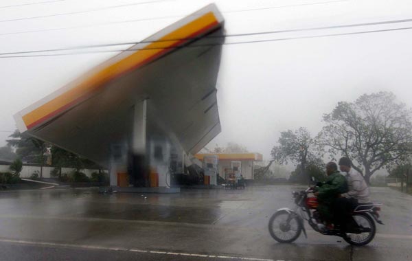 Filipinos drive past a damaged gasoline station caused by typhoon Megi in Isabela province, northern Philippines. EPA)