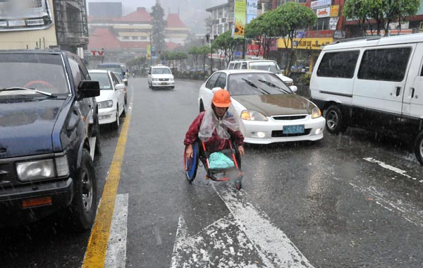 A physically challenged resident braves heavy rains and strong wind as he he heads home in a wheelchair in Baguio City, Benguet, north of Manila. (AFP)