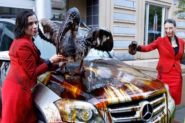 Members of environmental group Greenpeace pose around a luxury car covered by oil, outside the European carmakers association ACEA office in Brussels. (REUTERS)