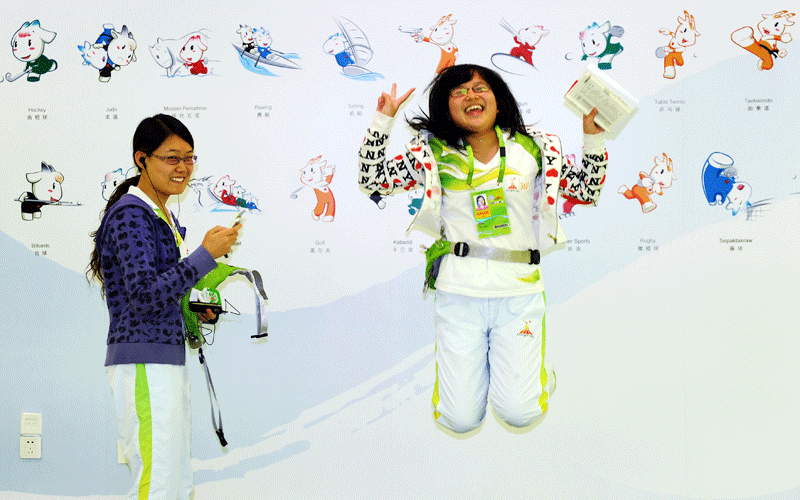 A hostess jumps as she poses for a picture in front of a poster for the 16th Asian Games in Guangzhou.  The 2010 Asian Games are held in Guangzhou, China, from November 12-27 and will be the biggest ever, with 45 countries and territories taking part in 42 sports.  (AFP)